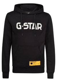 Sudadera negra con el logotipo blanco de "G-STAR", cordones ajustables, bolsillo estilo canguro en la parte frontal y etiqueta de la marca amarilla en el dobladillo. Textura de tela suave.