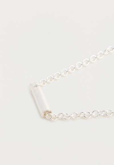 Pulseira de corrente prateada com fecho cilíndrico, elos planos e acabamento polido, destacando uma textura suave e um design elegante.