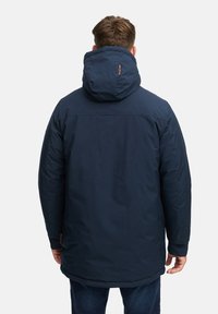 Marineblå parkas med hette, med en avslappet passform, glatt tekstur og et logo på ryggen. Knelang design.