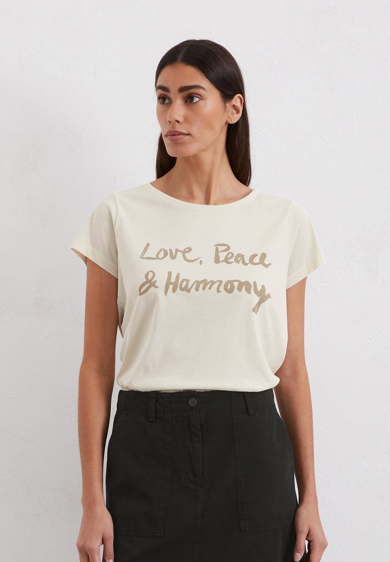 Cremfarbener T-Shirt mit kurzen Ärmeln, das auf der Vorderseite mit goldener Schrift "Liebe, Frieden & Harmonie" versehen ist. Hergestellt aus weichem Stoff und mit lässiger Passform.