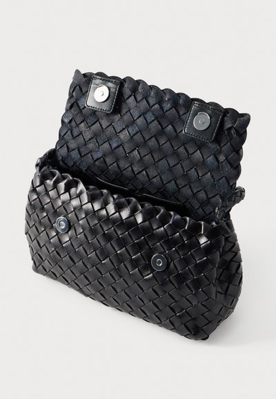 Μαύρη τσάντα ώμου από πλεγμένο δέρμα με υφή στην εξωτερική πλευρά, κλείσιμο με κουμπιά και ανοιχτό άνω μέρος που αποκαλύπτει λεία εσωτερική επένδυση.