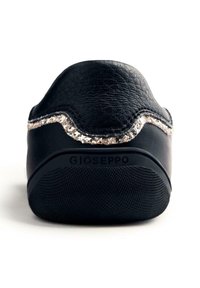 Zapato negro de piel sin cordones con suela texturizada, adornado con un borde de purpurina metálica, y un diseño redondeado con un sutil logotipo.