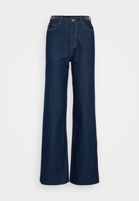 Jeans larges bleu foncé en denim avec un design classique à cinq poches, des coutures renforcées et un accent en métal circulaire sur la ceinture.