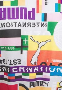 Wielokolorowa tkanina z nadrukami graficznymi. Wyróżniający się tekst "PUMA" w kolorze fioletowym, różne kształty oraz biały logo kota na jaskrawym tle.