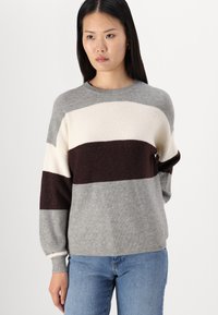 Pull en tricot rayé gris, crème et bordeaux ; présente une texture côtelée et des manches longues avec une coupe décontractée et un col rond.