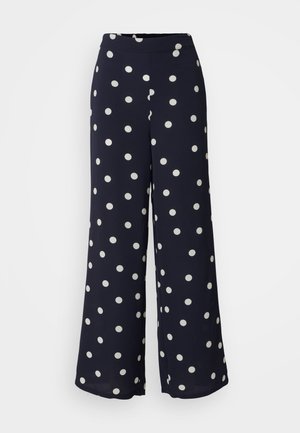 Pantalons amples bleu marine à pois blancs, avec une taille élastique. Fabriqués en tissu léger et lisse.