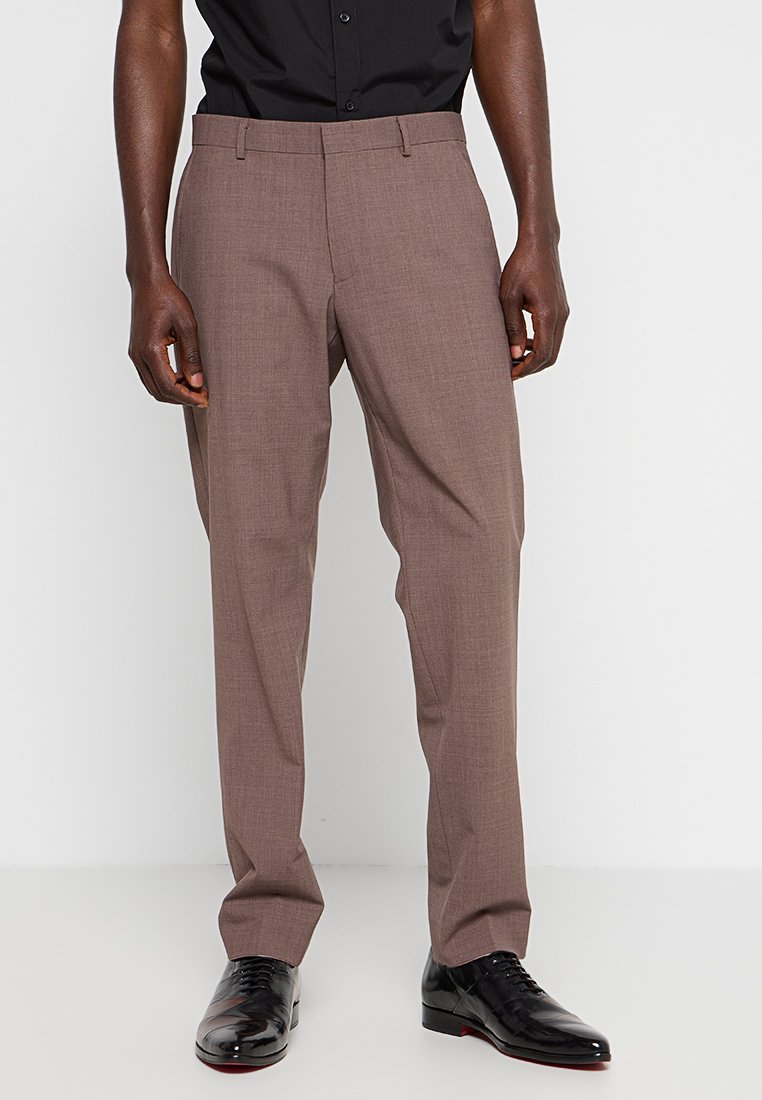 Pantaloni marroni su misura con una sottile trama, tasche standard e un design a gamba dritta, indossati con scarpe nere e una camicia abbinata.
