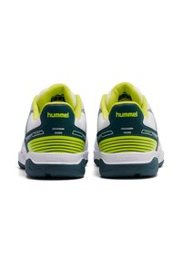 Białe buty sportowe z zielonymi i żółtymi akcentami, z siateczkową cholewką, wyściełanym kołnierzem i teksturowaną gumową podeszwą, oznaczone marką "hummel".