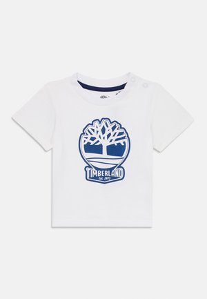 Witte katoenen T-shirt met korte mouwen, met een blauw Timberland-logo en boomgrafiek. Twee drukknoopjes op de schouder voor gemakkelijk aantrekken.