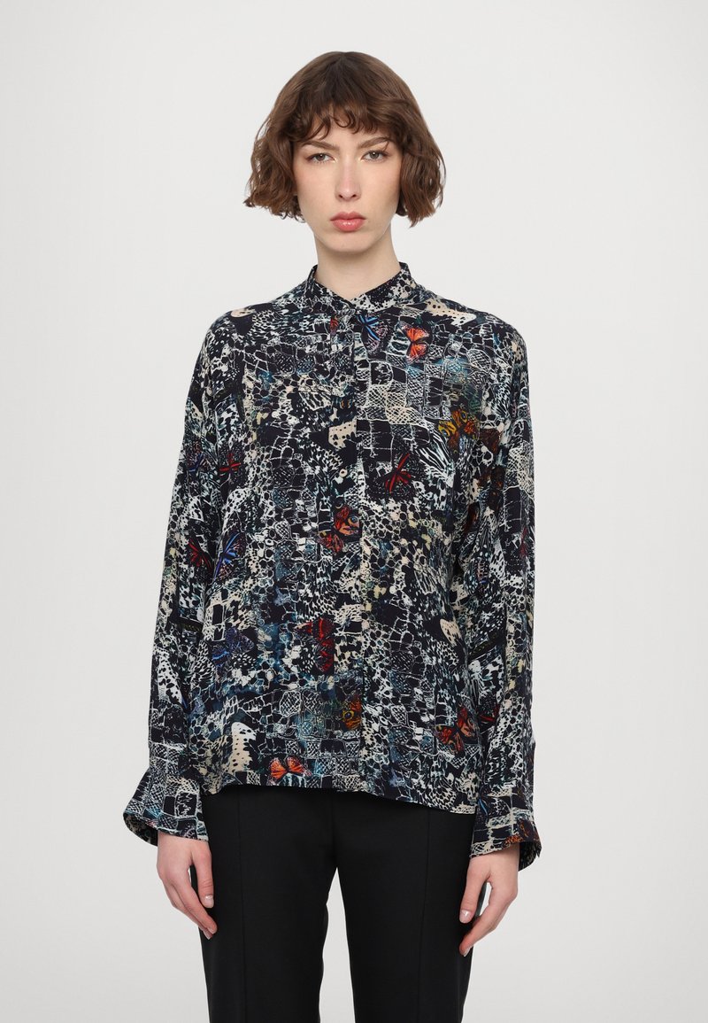 Long-sleeve blouse with a black base, featuring a mixed pattern of colorful butterflies and abstract designs. Soft, lightweight fabric.