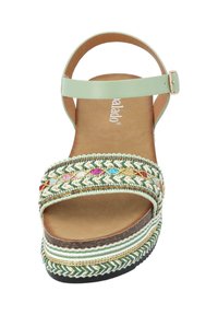 Sandalia de tiras verdes con una amplia banda decorativa trenzada que presenta acentos multicolores. Plantilla texturizada y diseño de suela en capas.