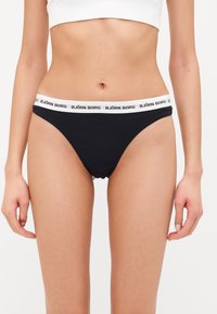 Black cotton bikini briefs featuring a white elastic waistband with "BJÖRN BORG" logo. Smooth texture and standard cut design.