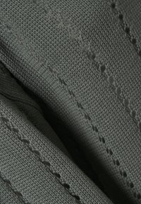 Gros plan sur un tissu tricoté gris foncé avec des rangées diagonales de petits trous allongés créant un motif en dentelle.