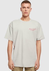 Lysegrå bomulds-t-shirt med korte ærmer og rund halsudskæring, der har rød tekst "italiensk cuisine" på venstre brystområde.