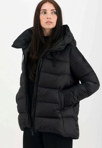 Giacca a vento nera con un ampio cappuccio, chiusura a zip e tasche a patta. Presenta un design trapuntato e un tessuto testurizzato per garantire calore.