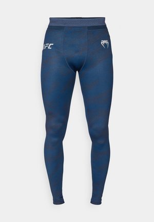 Leggings deportivos azules con un sutil patrón tonal, cinturilla elástica y logo de UFC en la cadera izquierda. Confeccionados con una tela elástica y transpirable.