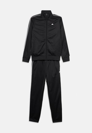 Survêtement noir deux pièces avec des bandes blanches sur les manches et les pantalons, veste zippée avec col montant, et poches avant sur la veste et les pantalons.