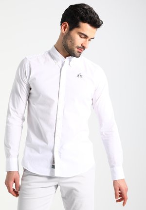 Camicia bianca a maniche lunghe con bottoni e colletto classico, caratterizzata da un logo ricamato discreto sul petto, realizzata in morbido cotone.