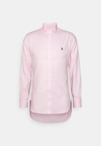 Camisa de mangas longas rosa-claro com colarinho clássico. Possui um fecho com botões e um logótipo bordado no lado esquerdo do peito. Tecido de algodão suave.