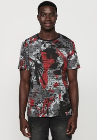 Tricou cu mânecă scurtă în gri, negru și roșu, cu modele abstracte, inclusiv text și stropi; material ușor, cu gât rotund.