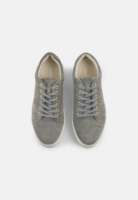 Hallhalli halluxed sneakers kuldpruunide silmadega, lamedate hallide paeltega ja valge kummitald. Disain sisaldab ümmargust sõrmeosa ja minimaalset brändingut.