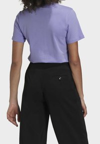 Lila kortärmad t-shirt med rund halsringning, tillsammans med svarta högmidjade byxor som har en bakficka och knappdetalj.