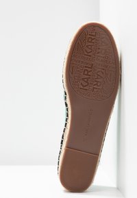 Semelle en caoutchouc marron avec logo Karl Lagerfeld. Tige en tissu tissé noir avec accents verts. Bordure en jute style espadrilles le long du bord. Taille 37.