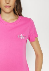 Svijetloružičasta pamučna majica kratkih rukava, s malim sivim logotipom Calvin Klein Jeans na području prsiju.