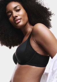 Sostén negro hecho de tela suave con acentos de encaje. Presenta una forma contorneada y tirantes ajustables, exhibiendo un diseño texturizado.