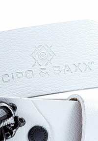 Bracelet en cuir blanc texturé avec logo embossé "CIPO & BAXX". Doté de quincaillerie métallique noire, y compris un accessoire décoratif.