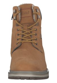 Botín de cuero marrón con un cuello forrado de peluche, punta redonda, cordones amarillos, ojales de metal y una suela de goma texturizada.