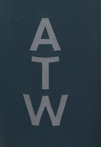 Mørkt stofbaggrund med store, lodret justerede grå bogstaver "A", "T" og "W" centreret fra top til bund.