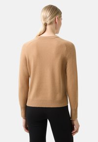 Pull en laine couleur camel avec un ourlet et des poignets en côtes, présentant un encolure ronde et des manches raglan, vu de dos.