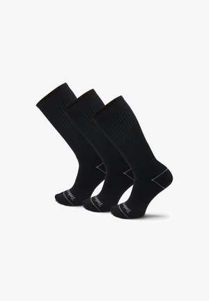 Schwarze kniehohe Socken mit gerippter Struktur, verstärkter Zehen- und Fersenpartie, einem kontrastierenden goldenen Streifen am oberen Rand und Markenlogo auf der Sohle.