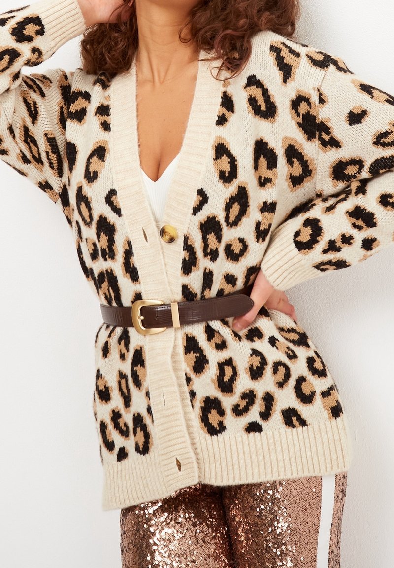Cardigan leopard in beige, con macchie nere e beige, polsini a coste, scollatura a V e una cintura marrone in vita.