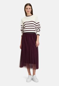 Pull blanc avec des rayures bordeaux, associé à une jupe en tulle bordeaux jusqu'au genou et des baskets blanches. Texture tricot lisse et transparente.