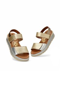 Chanclas metálicas doradas con dos tiras amplias, parte superior de cuero, plantilla acolchada y suela texturizada. Acentuadas con detalles en plata.