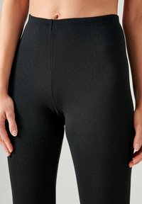 Leggings de punto negros con un patrón texturizado. Diseño de cintura alta, material acanalado y cinturilla elástica, que ofrecen un ajuste ceñido.