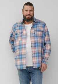 Koszula w kratę w kolorach niebieskim, czerwonym i białym, z długimi rękawami, dwoma kieszeniami na piersi oraz zapięciem na zatrzaski, noszona na białej koszuli.