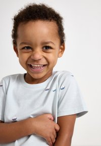 T-shirt in cotone azzurro chiaro con ricami di barche in rosso e blu. Maniche corte con scollatura rotonda classica.