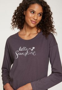 Majica dugih rukava tamno ljubičaste boje od mekog materijala s bijelim natpisom u rukopisnom stilu koji glasi „hello Sunshine“ uz cvjetne akcenti.