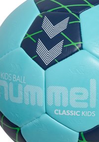 Pallone da calcio blu e blu navy con accenti verdi, pannelli esagonali, superficie testurizzata, con strisce bianche e nome del marchio stampato in grassetto.