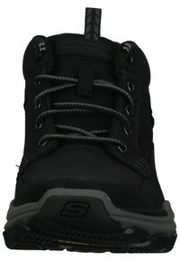 Botas de senderismo negras con parte superior de textil, collar acolchado, cordones grises, ojales de metal y suela de goma texturizada. Detalle de refuerzo en la puntera.
