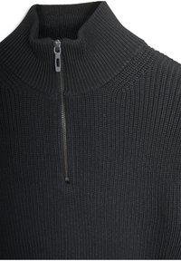 Zwarte geribde pullover met een hoge kraag, voorzien van een halve rits. Gelaagd stof en een gladde ritsbeslag bieden functionele details.