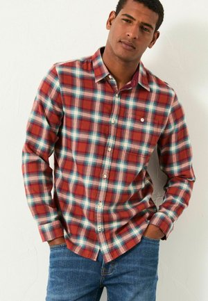 Rot-blau karierte Button-up-Bluse mit langen Ärmeln, ausgestattet mit einer Brusttasche und weißen Knöpfen, kombiniert mit blauen Jeans.