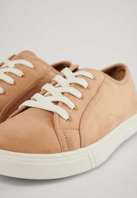Sneaker in suede rosa con lacci bianchi, punta arrotondata e suola in gomma testurizzata con sottili dettagli di cucitura.