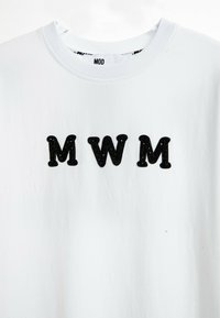 Camiseta de algodón blanca con tres letras bordadas en negro "MWM". Manga corta y un cuello redondo con una textura suave.