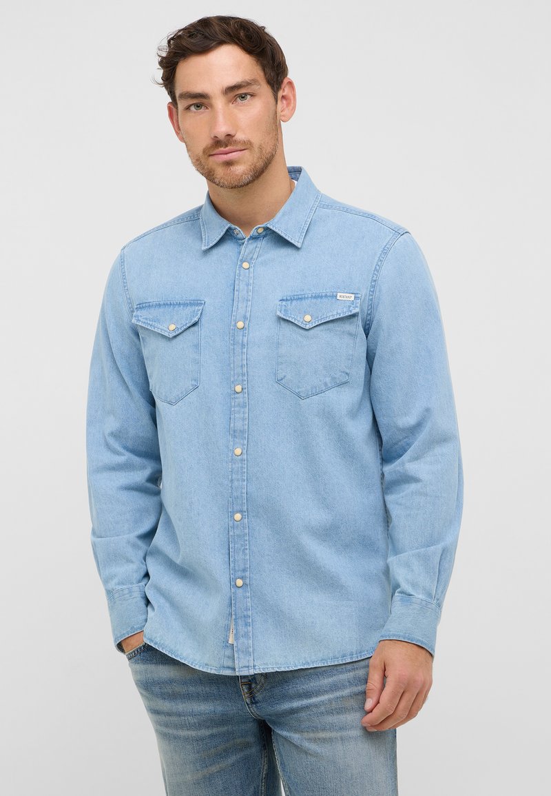 Jasnoniebieska koszula dżinsowa z kołnierzykiem zapinanym na guziki, dwiema kieszeniami na piersi oraz długimi rękawami z zapięciem na guziki. Gładka tekstura, casualowy design.