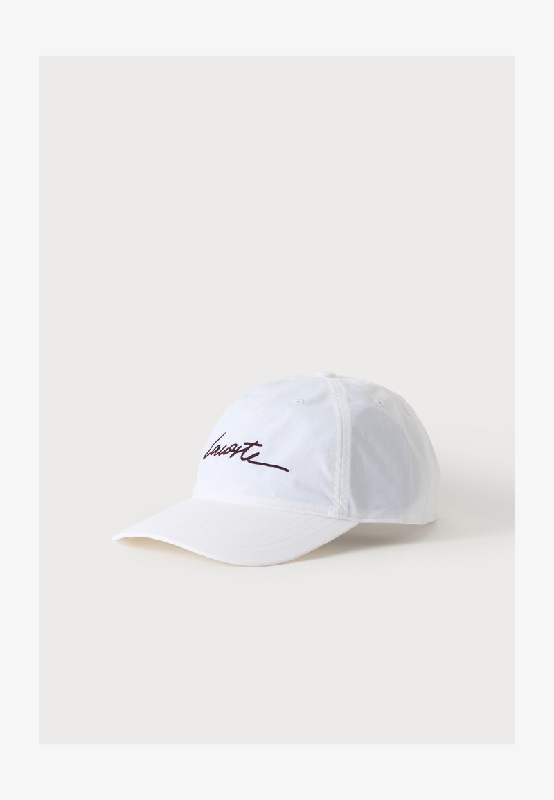 Casquette de baseball blanche avec une visière incurvée et un texte en cursive noire à l'avant, présentée sur un fond clair uni.