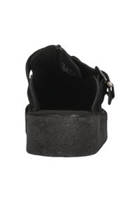 Svarta skor med en strukturerad gummiyttersula. Har en öppen bakdesign med justerbar spänne. Inuti fodrad med mjukt material.